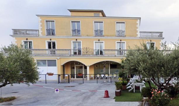 Edificio giallo a tre piani con balconi e giardino.