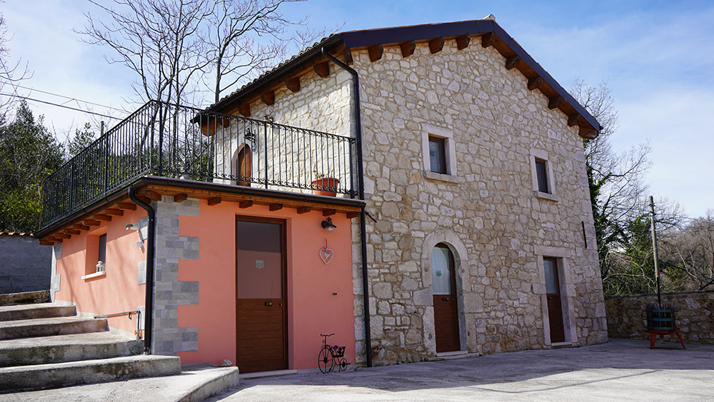 Casa in pietra con balcone e pareti rosa.